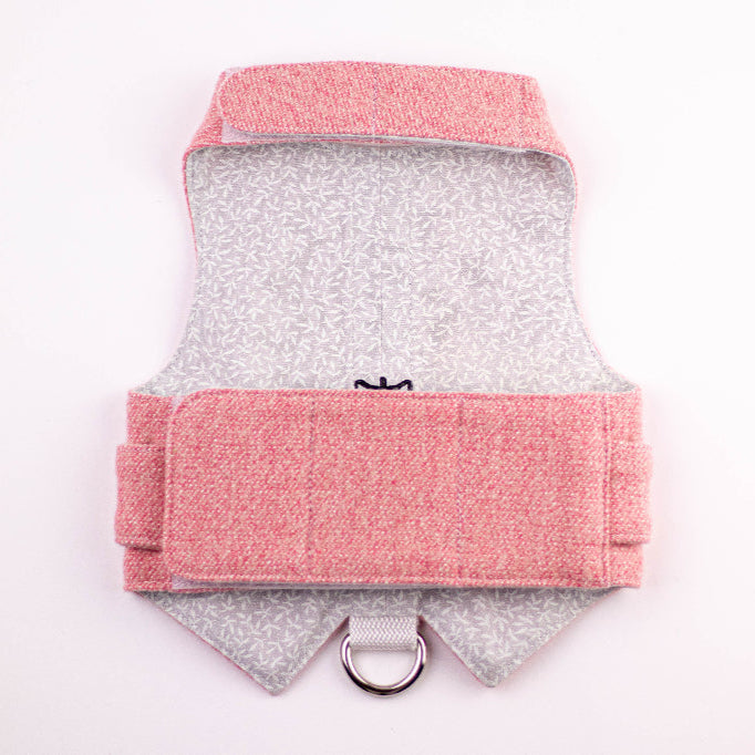 The inside of a pink tweed cat harness showing a light grey fabric lining with a subtle leaf pattern and a silver D-ring attachment.