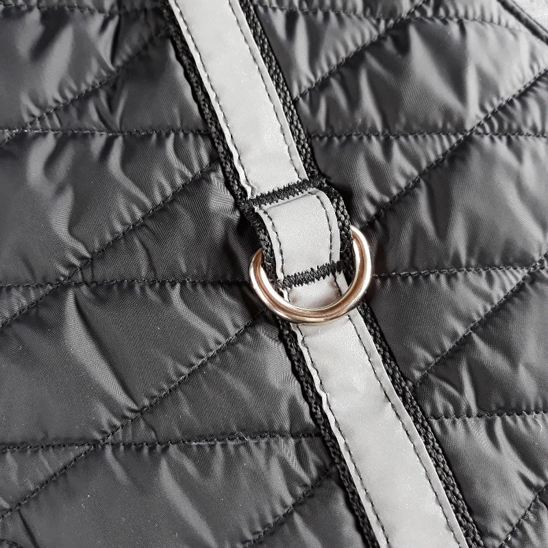 A quilted black cat harness with reflective silver stripes, circular reflective elements
