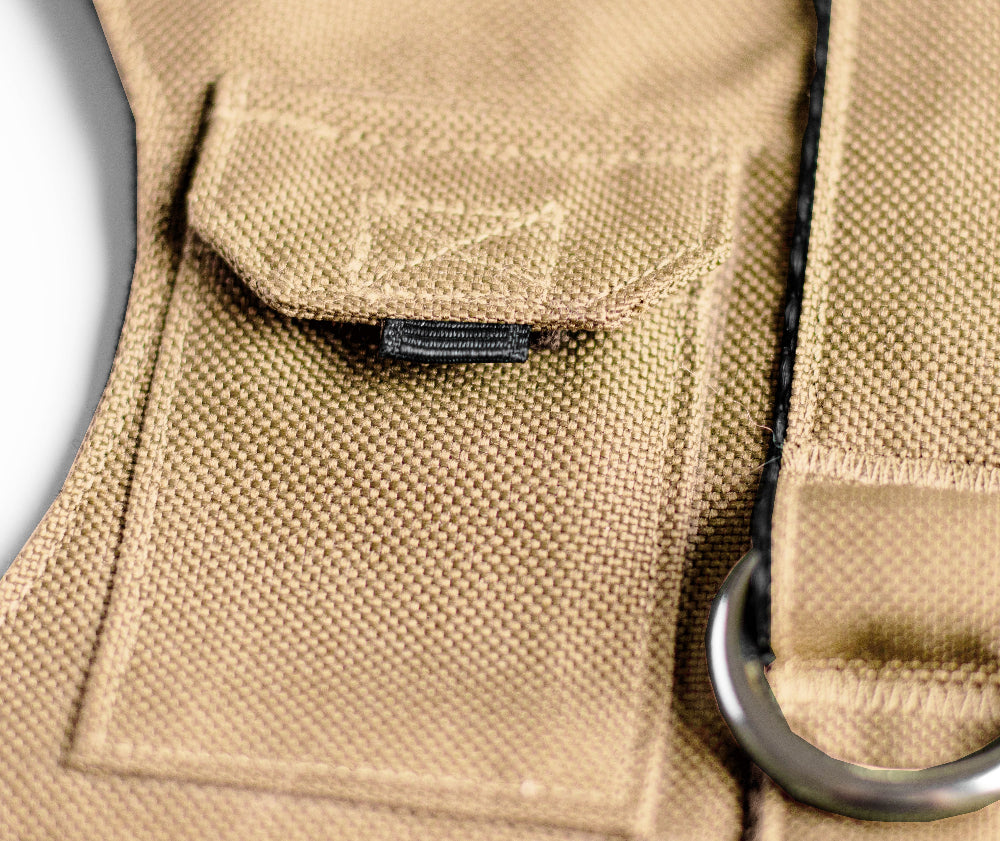 Tan pet harness designed with a utility vest appearance, featuring several small pockets, a leash attachment ring, and a customizable name patch.