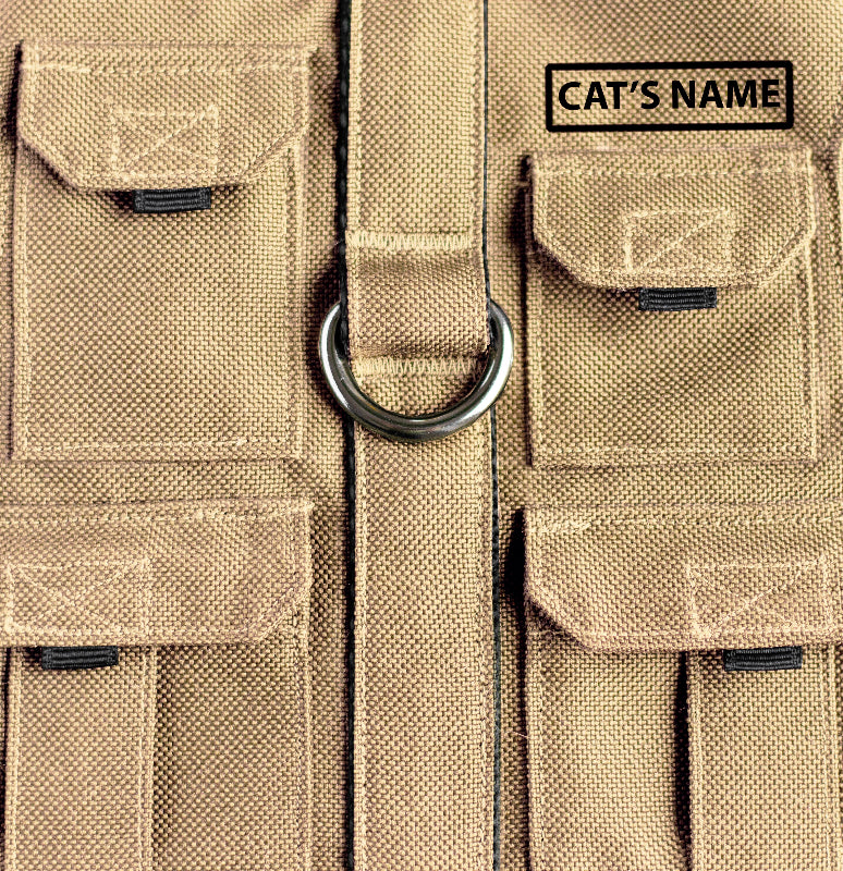 Tan pet harness designed with a utility vest appearance, featuring several small pockets, a leash attachment ring, and a customizable name patch.