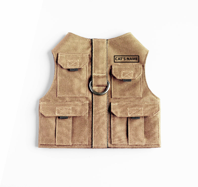 Tan pet harness designed with a utility vest appearance, featuring several small pockets, a leash attachment ring, and a customizable name patch.