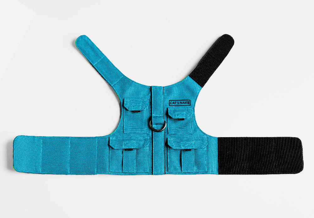 Cat harness designed with a utility vest appearance, featuring several small pockets, a leash attachment ring, and a customizable name patch.