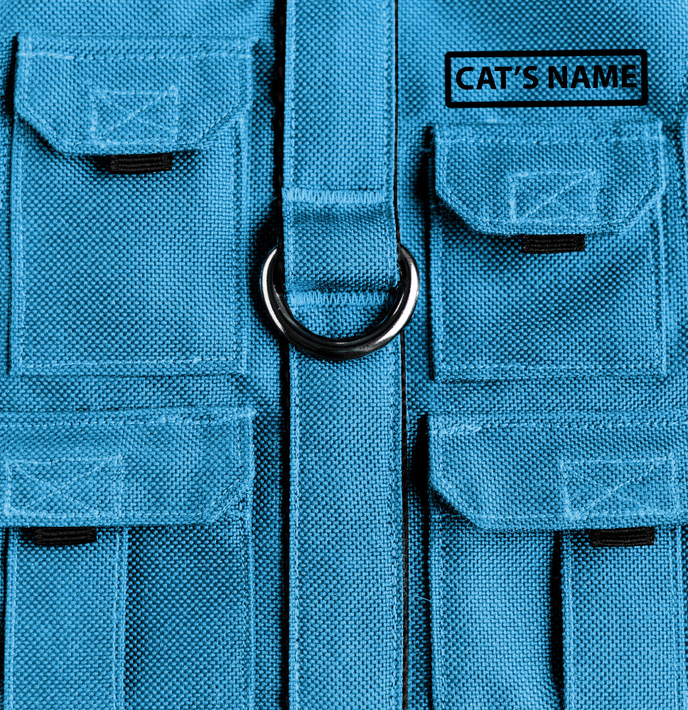 Cat harness designed with a utility vest appearance, featuring several small pockets, a leash attachment ring, and a customizable name patch.