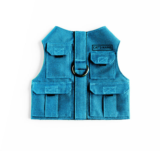 Cat harness designed with a utility vest appearance, featuring several small pockets, a leash attachment ring, and a customizable name patch.