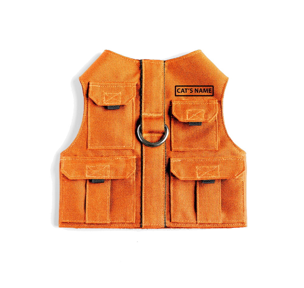 Cat harness designed with a utility vest appearance, featuring several small pockets, a leash attachment ring, and a customizable name patch.