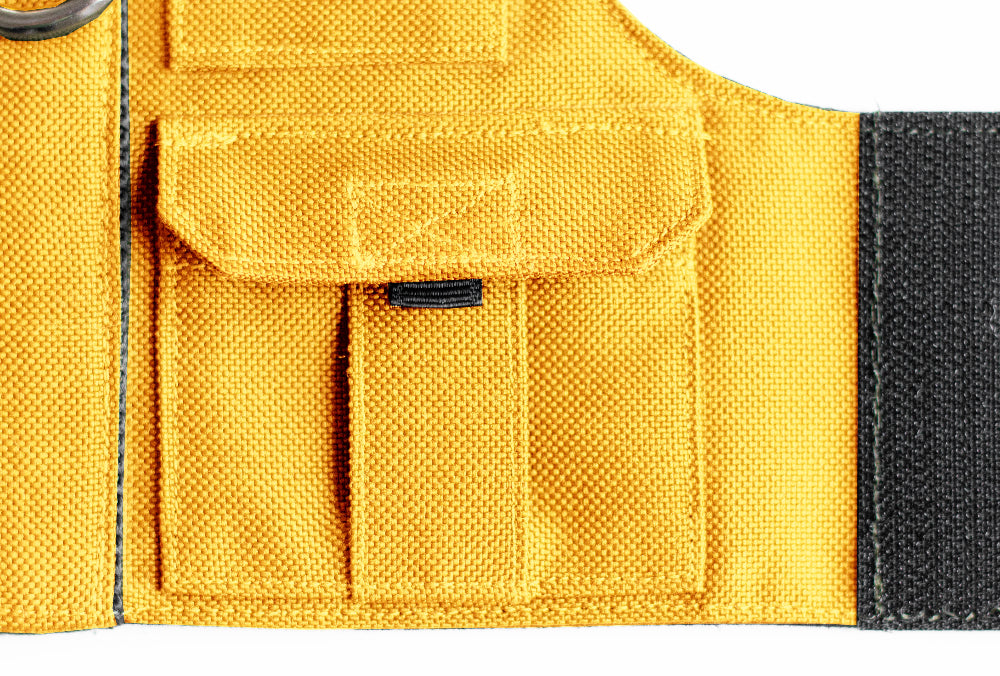 Cat harness designed with a utility vest appearance, featuring several small pockets, a leash attachment ring, and a customizable name patch.