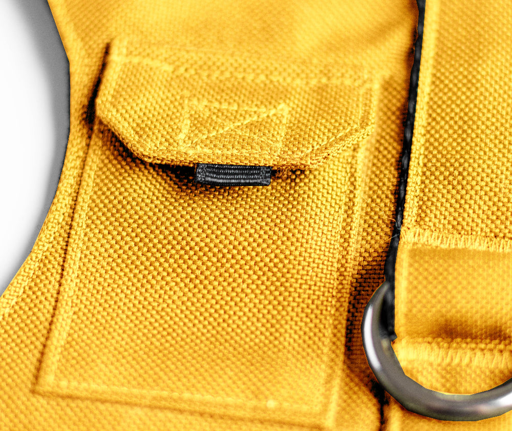 Cat harness designed with a utility vest appearance, featuring several small pockets, a leash attachment ring, and a customizable name patch.