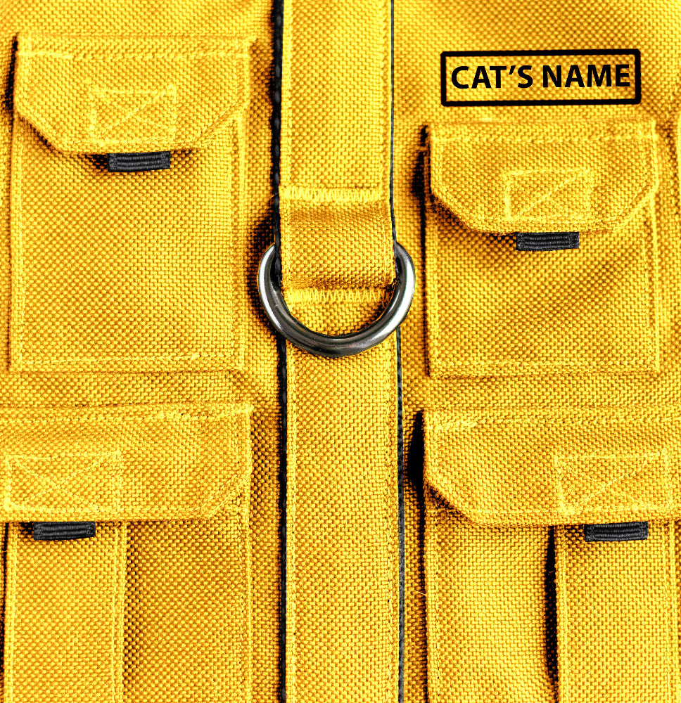 Cat harness designed with a utility vest appearance, featuring several small pockets, a leash attachment ring, and a customizable name patch.