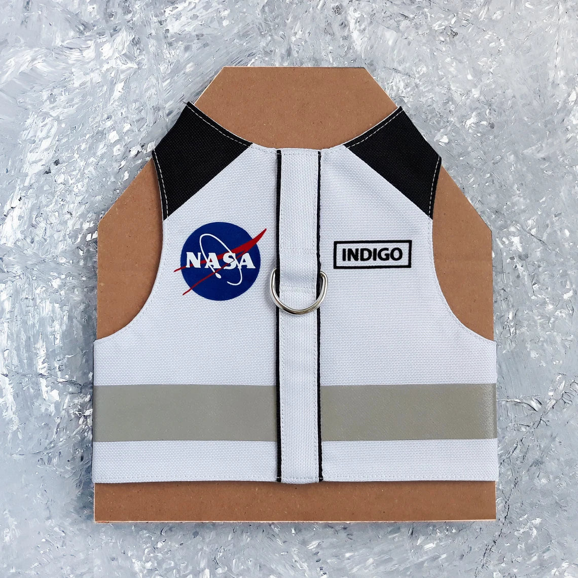 White cat harness with black shoulder accents, a NASA logo patch, a reflective silver stripe