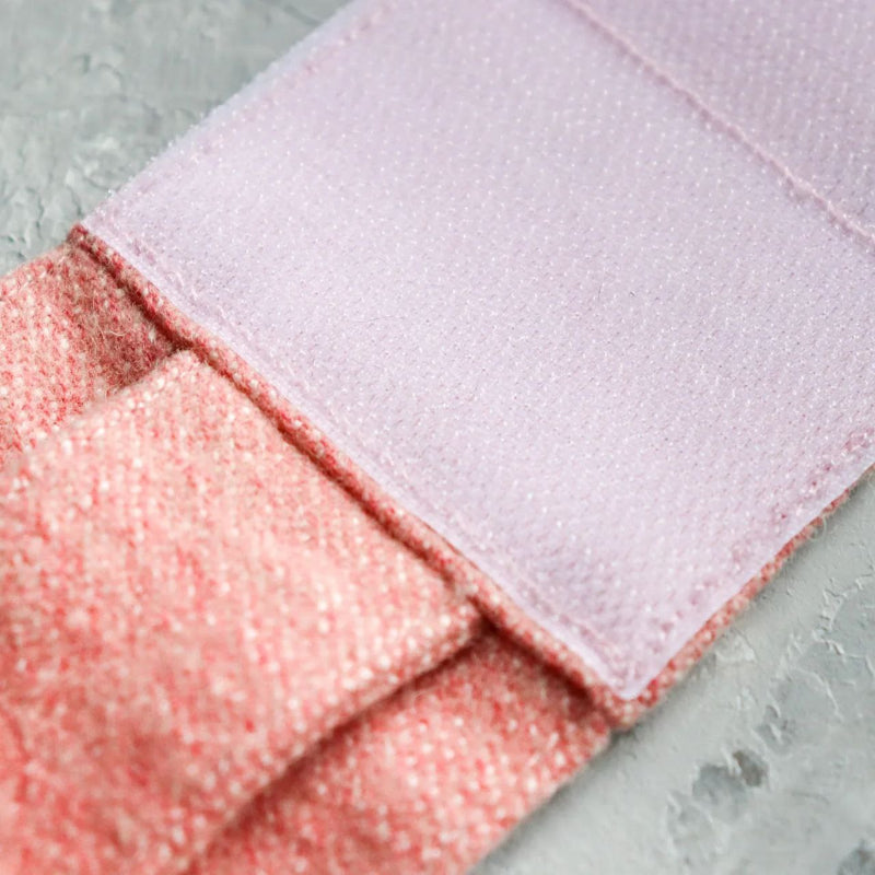 Close-up of a light pink Velcro strap attached to a pink tweed cat harness.