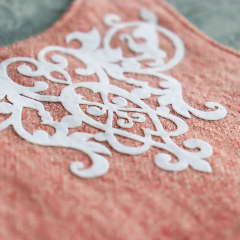 Close-up of ornate white decorative embroidery on a pink tweed cat harness.