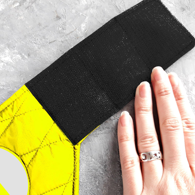 A quilted yellow cat harness with reflective silver stripes, circular reflective elements