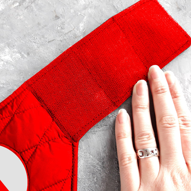 A quilted red cat harness with reflective silver stripes, circular reflective elements