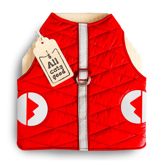 A quilted red cat harness with reflective silver stripes, circular reflective elements, and a brown "Allcatsgood" tag.