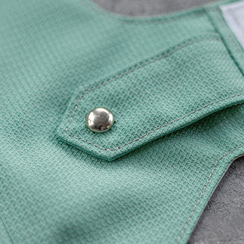 Close-up of an azure textured cat harness showing a small flap with a silver button accent and subtle stitching details.