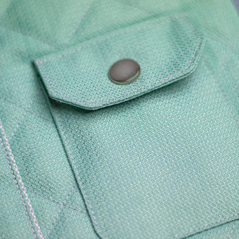 Light blue quilted cat harness with a vest-like design, featuring two small pockets with snap closures and a silver D-ring.