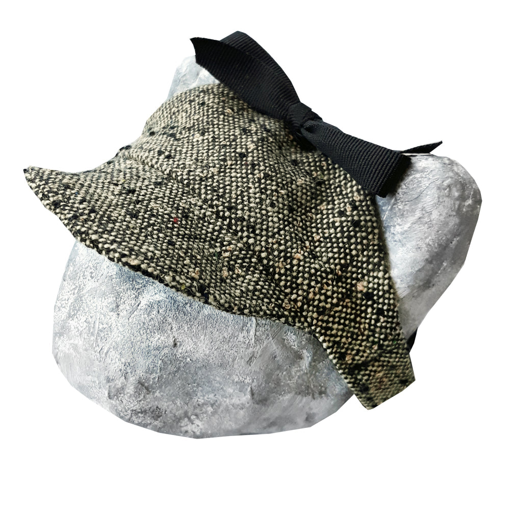 Tweed-style hat for a cat with a small brim and a black ribbon tied in a bow on top, shown on a grey textured surface.