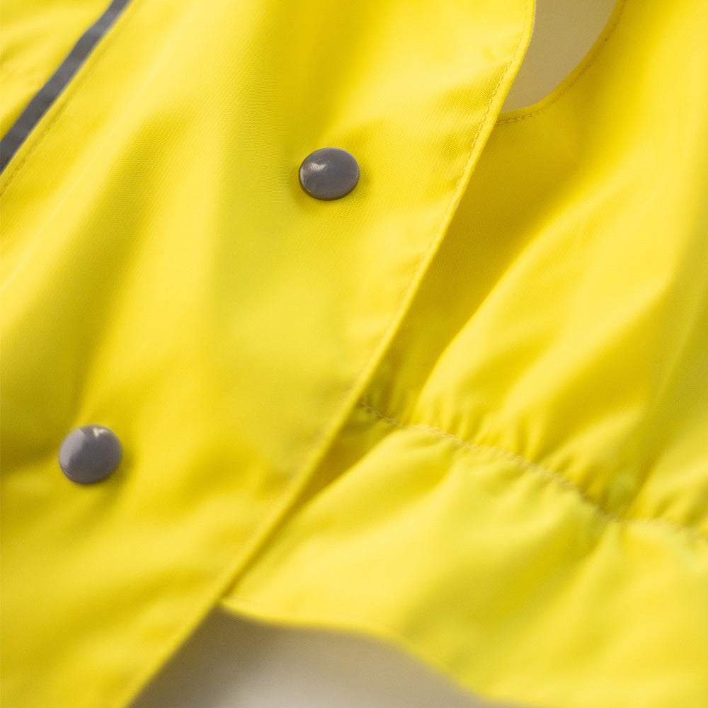 Close-up of grey snap closures on a bright yellow cat raincoat, showing the fabric and stitching details.
