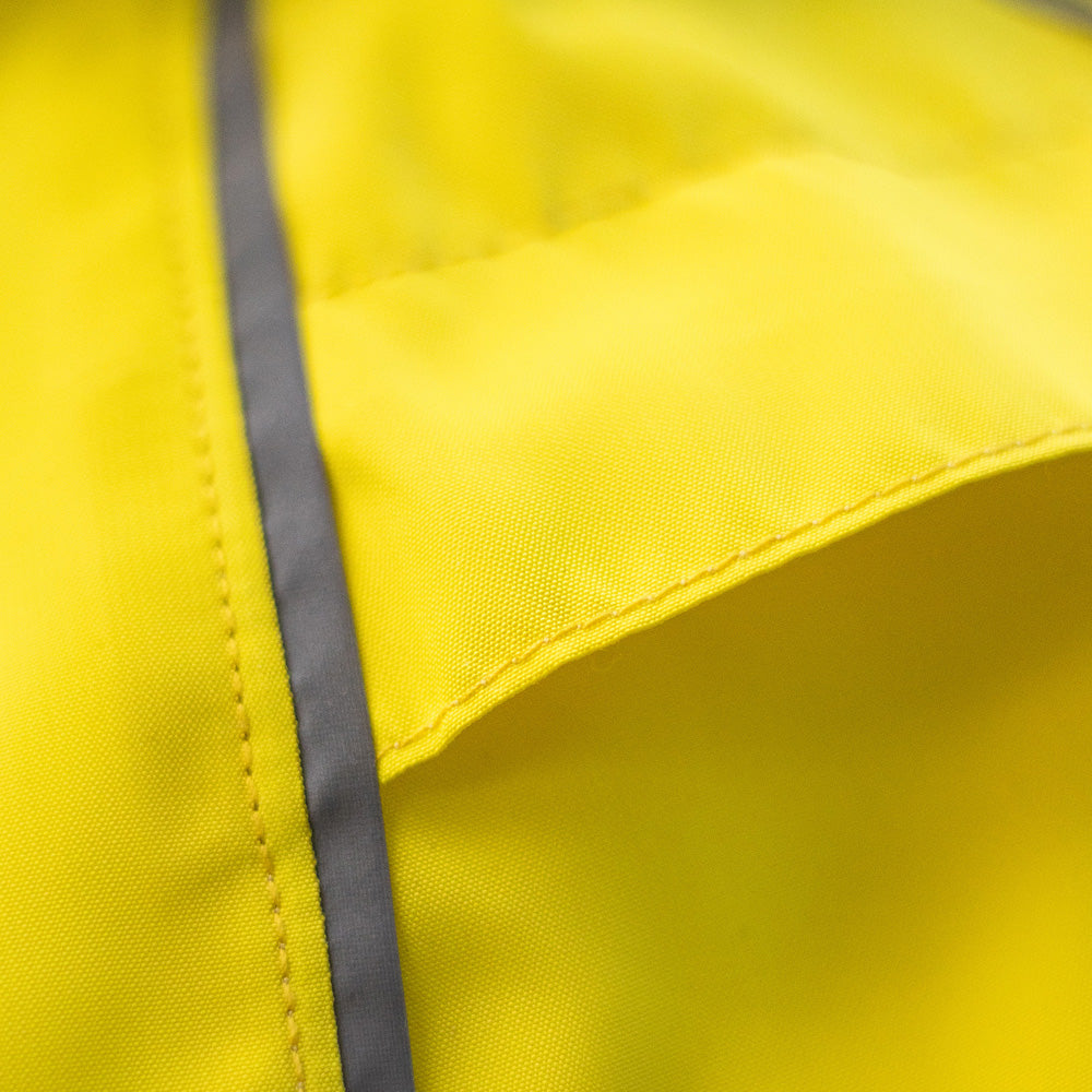 Close-up of grey snap closures on a bright yellow cat raincoat, showing the fabric and stitching details.
