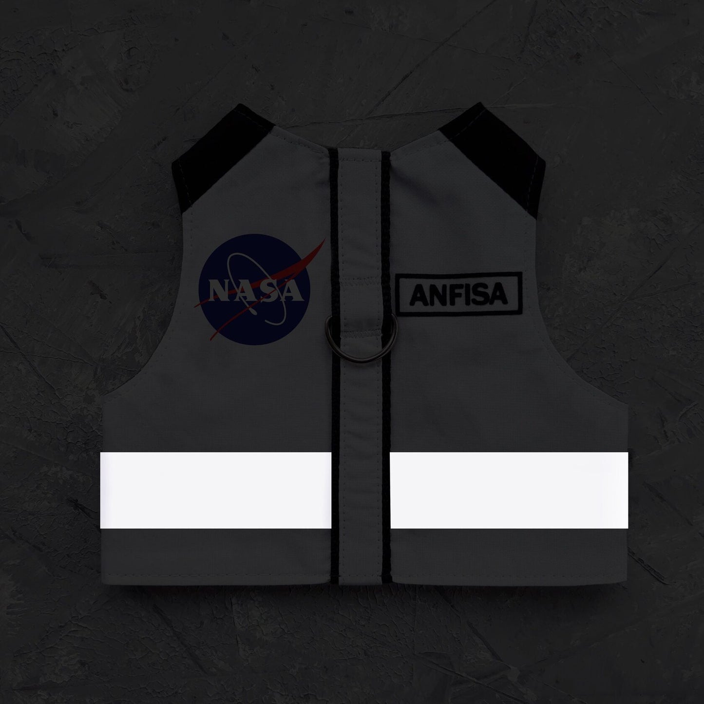 A dark grey cat harness with black shoulder accents, a glowing white reflective stripe, a NASA logo patch, and an "ANFISA" tag illuminated in low light.