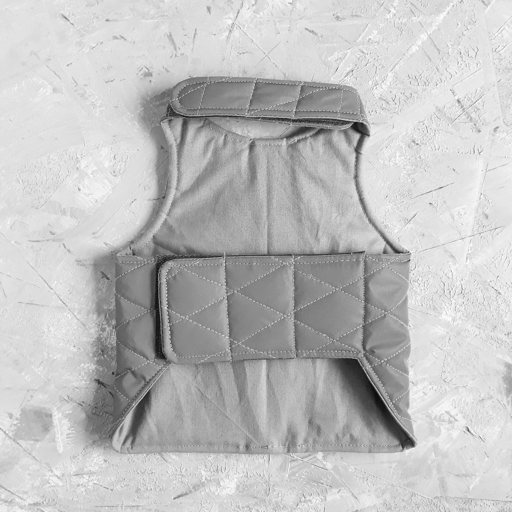 The inside of a light grey quilted cat harness showing a soft, patterned fabric lining and Velcro closures.