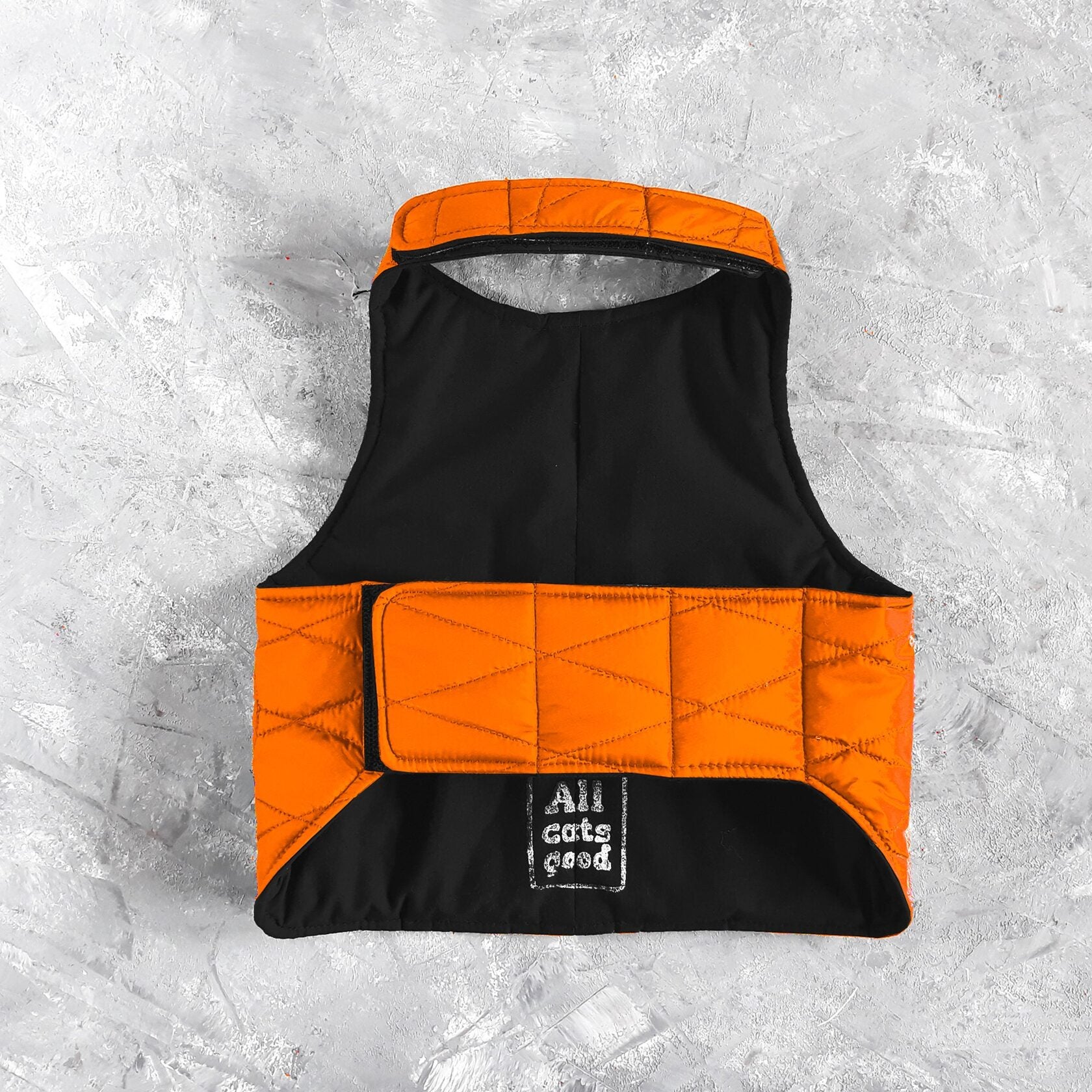 Inside of an orange quilted cat harness with black lining.