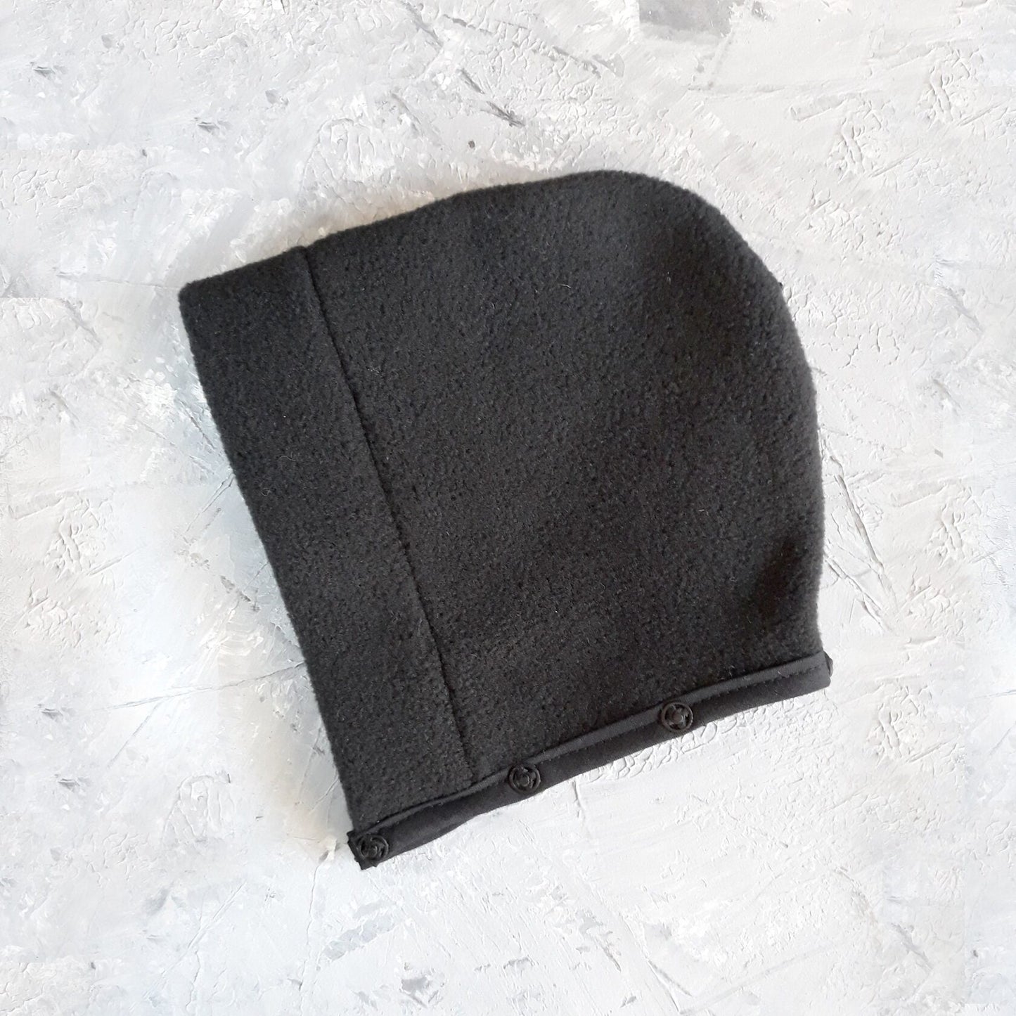 A black cat harness with a soft, fleece-lined hood and a D-ring for leash attachment.