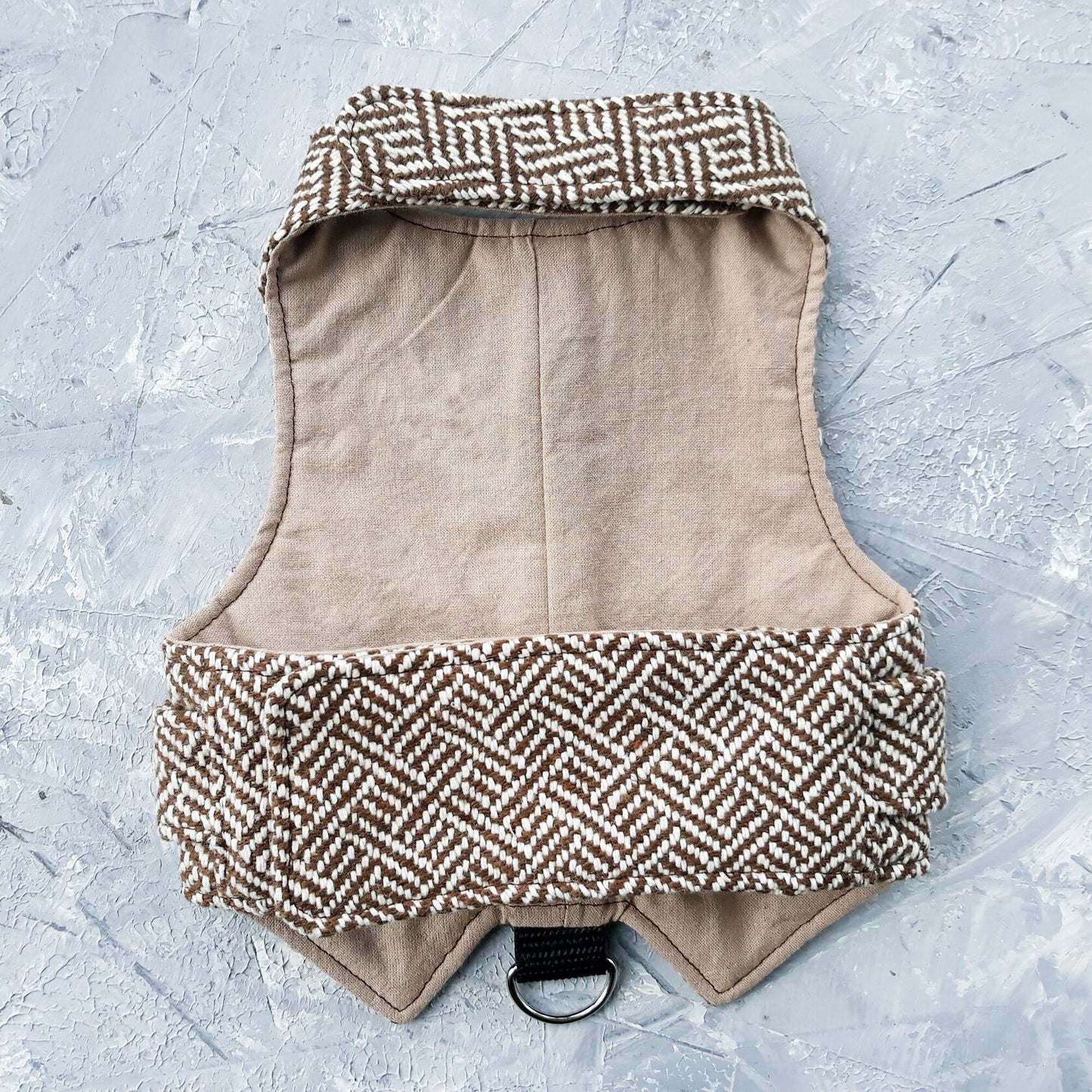 The inside lining of a brown tweed cat harness.