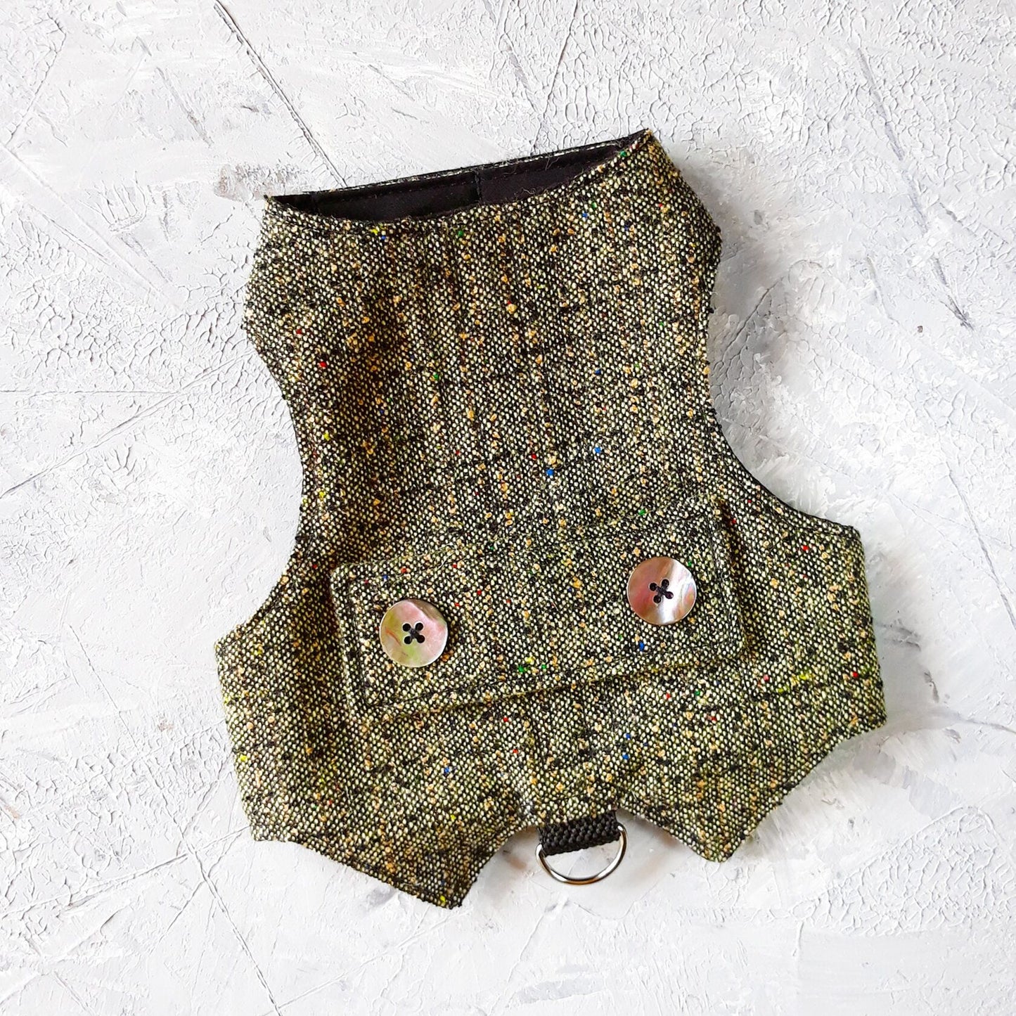 A grey tweed cat harness with colorful flecks, decorative mother-of-pearl buttons, and a silver D-ring.
