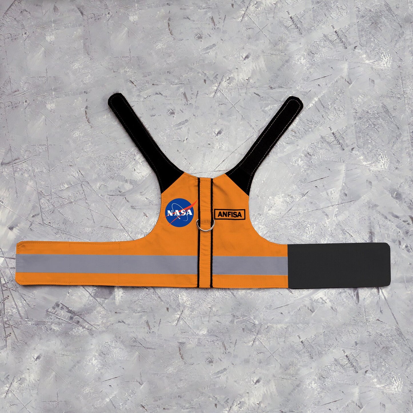 An orange cat harness with black shoulder accents, a NASA logo patch, a reflective silver stripe