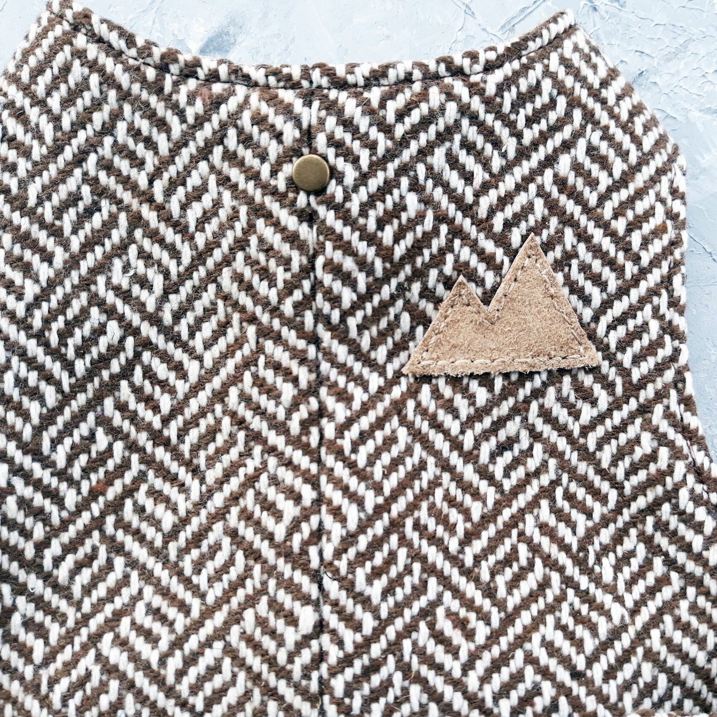 Close-up of the tweed fabric, button, and patch on a cat harness.