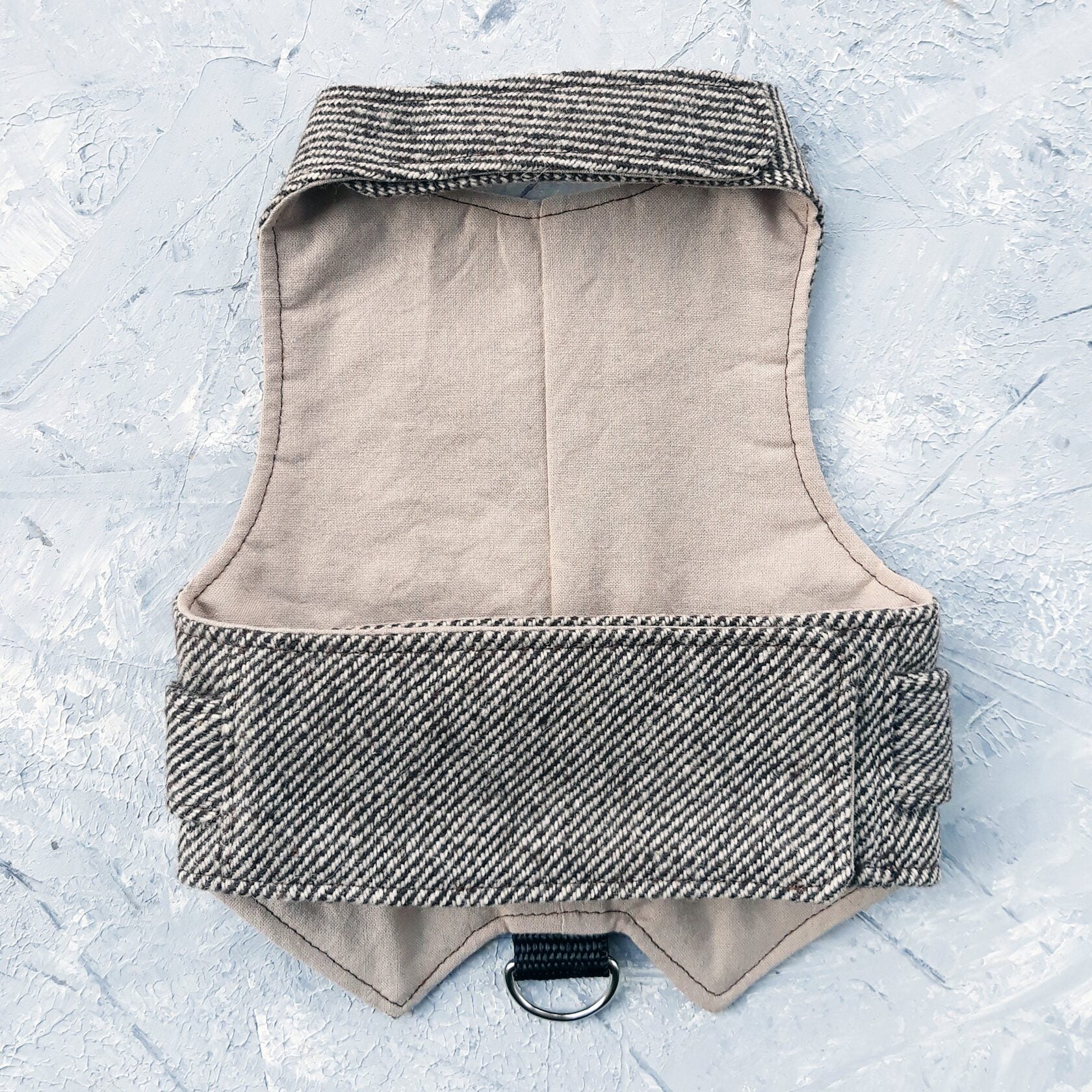 The inside lining of a brown tweed cat harness.