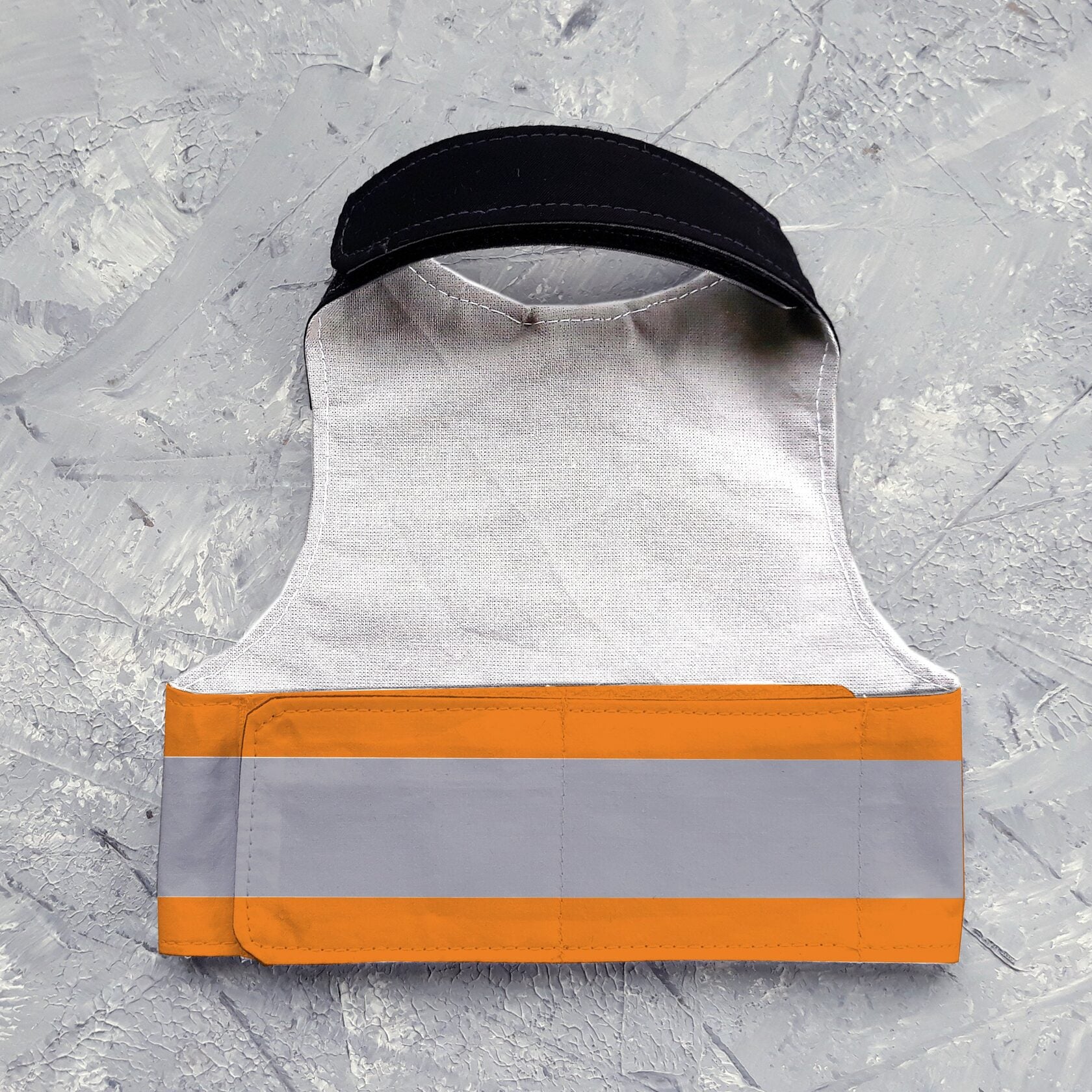 An orange cat harness with black shoulder accents, a NASA logo patch, a reflective silver stripe, and AirTag pocket