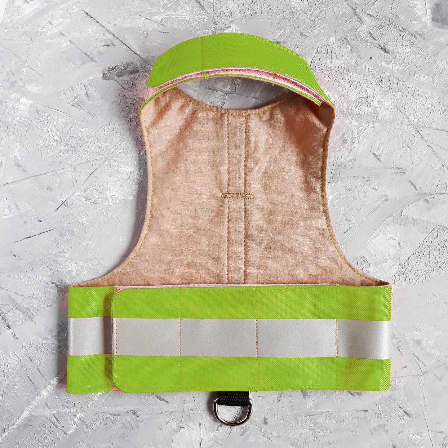 Interior view of a water-repellent green cat harness with a light-colored lining and reflective silver bands.