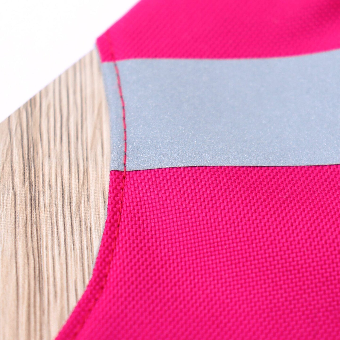 Close-up of a reflective silver stripe on a bright pink cat harness.