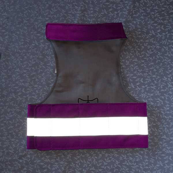 A bright pink cat harness with horizontal reflective silver stripes, a grey vertical strap, and a silver D-ring