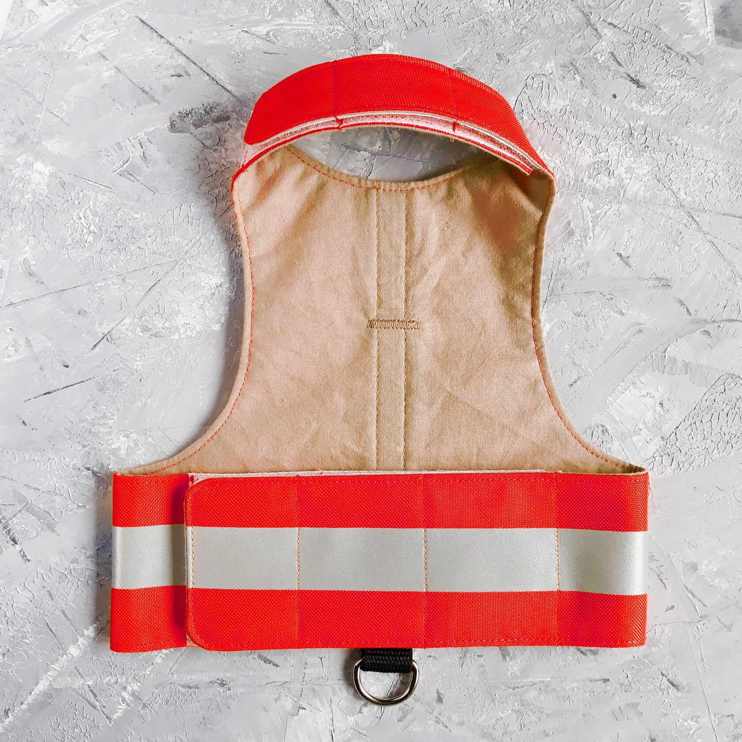 Flat lay of red safety vest for an emotional support animal, featuring two horizontal reflective silver stripes and the white text "EMOTIONAL SUPPORT ANIMAL" stacked in the center, with a black leash attachment loop and silver D-ring at the bottom.