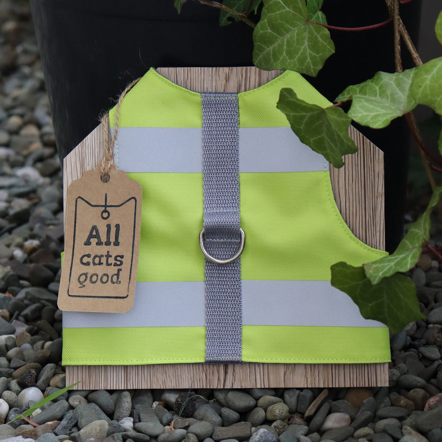 High-visibility green pet harness with reflective bands, a central grey strap, a metal leash attachment ring, and a brand tag.