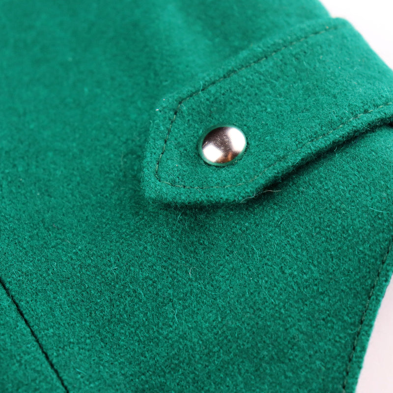 Close-up of a green wool cat harness showing a small flap with a silver button accent and the black inner lining.