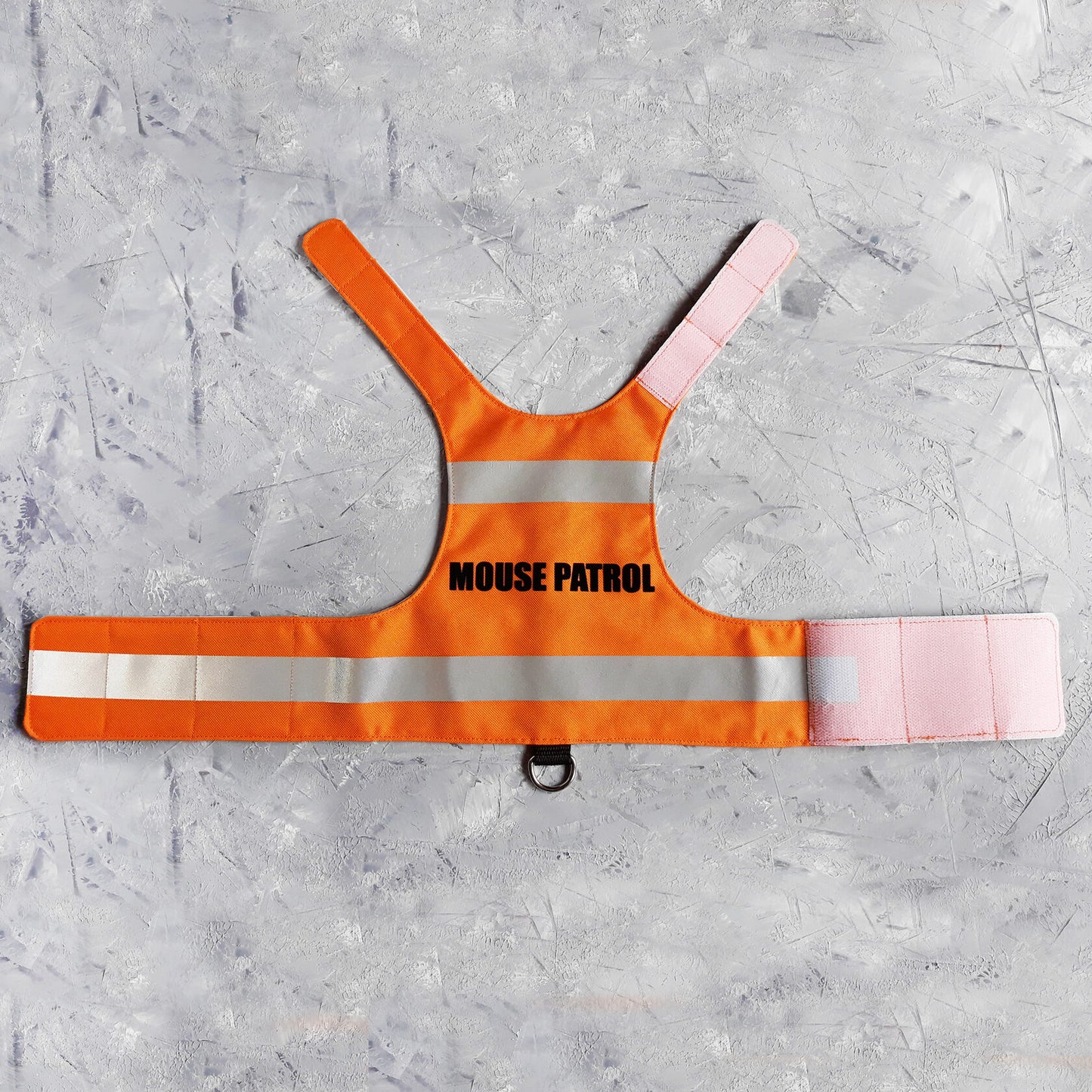 A bright orange safety vest with horizontal reflective white stripes and the text "MOUSE PATROL" in black capital letters. A black loop with a silver D-ring is at the bottom.