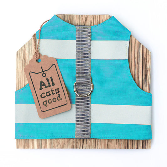 A turquoise and reflective striped cat harness with a grey vertical strap and a brown tag that reads "Allcatsgood."