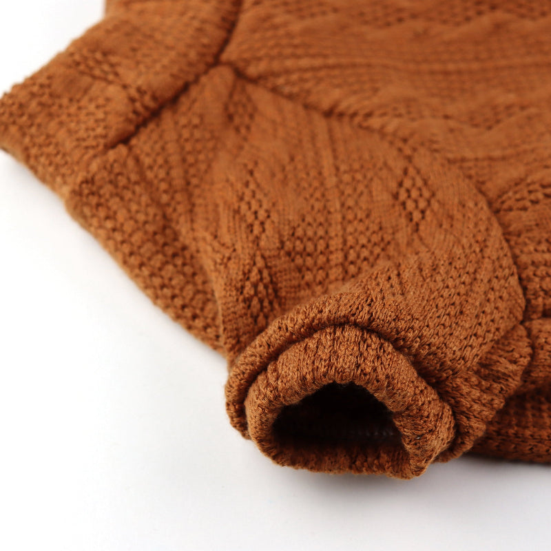 Orange cable-knit sweater for a cat with a high ribbed turtleneck, short sleeves, and a small white label near the hem.