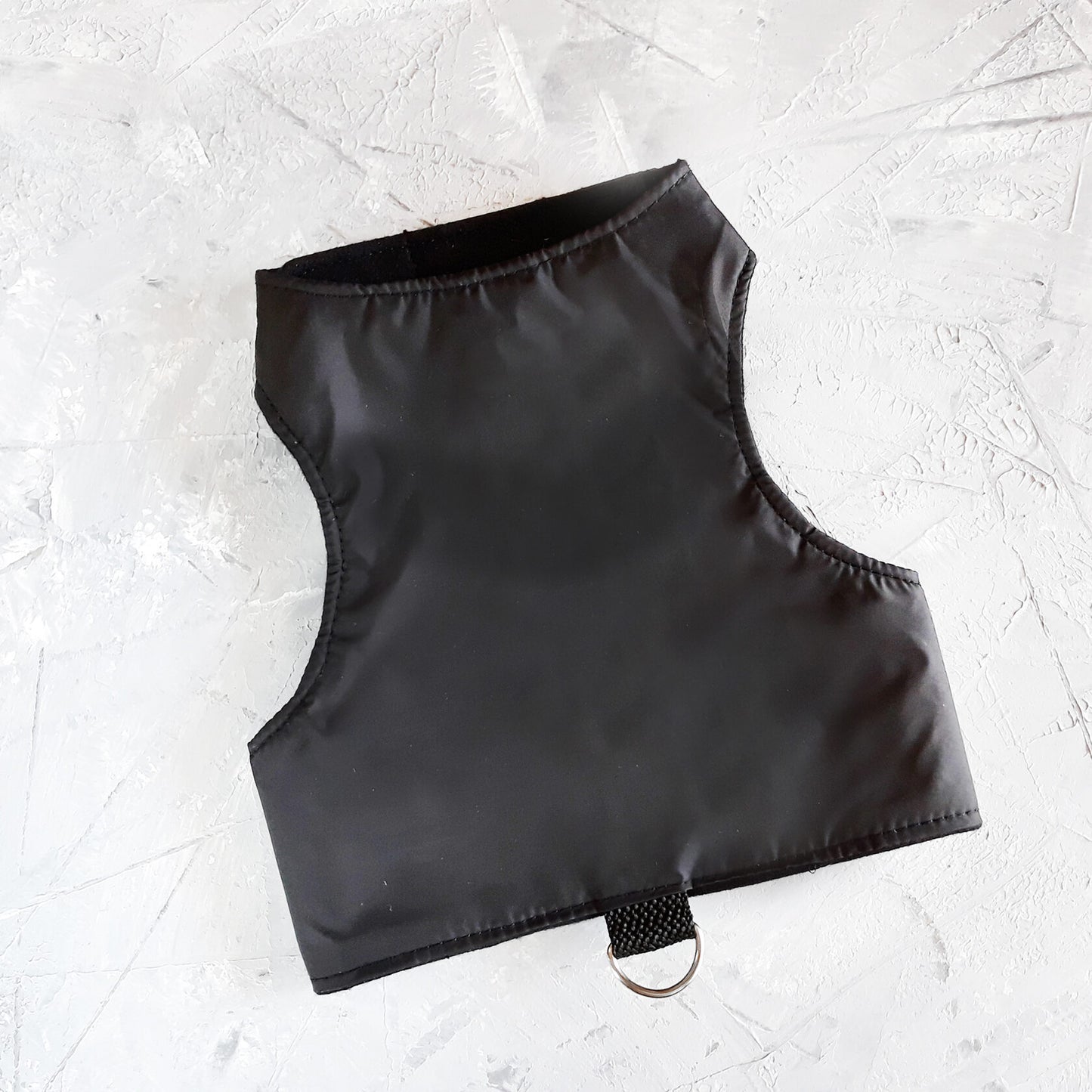 Black cat harness with a soft black lining and a black leash attachment loop with a silver D-ring.