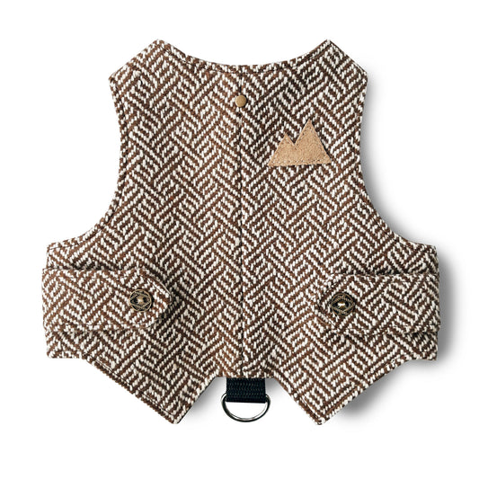A cat harness made from brown tweed fabric with a distinctive geometric pattern. A functional D-ring connected by a black strap.