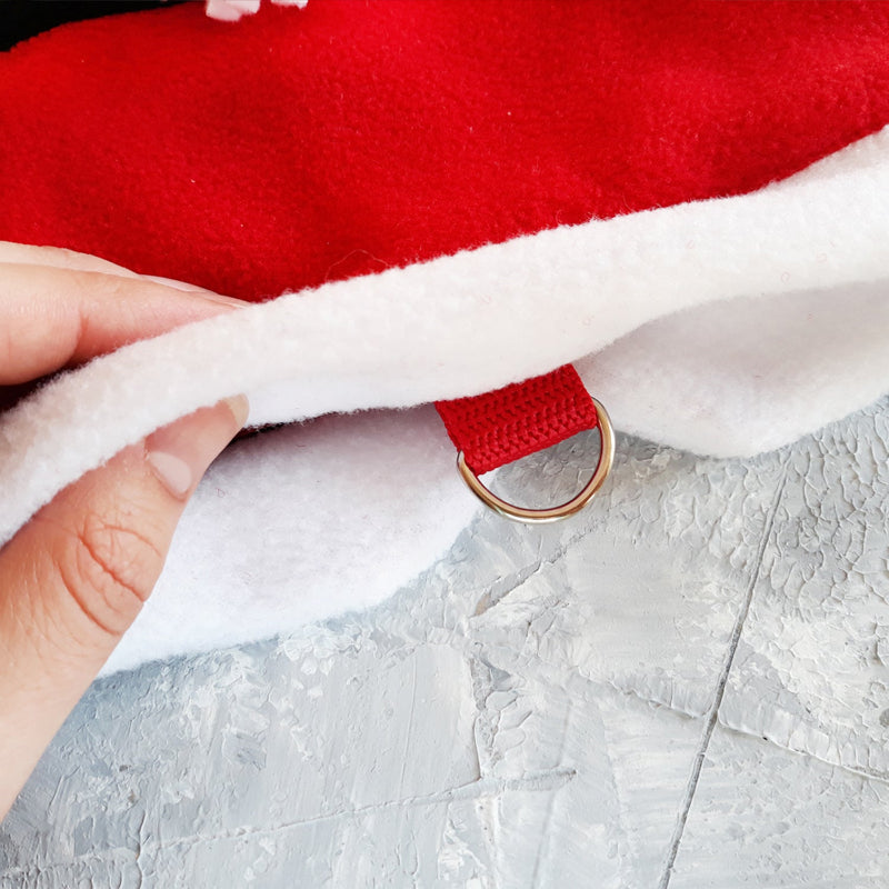 Detailed view of the leash attachment point on a festive Santa cat harness, showing the metal D-ring and red fabric loop being held.