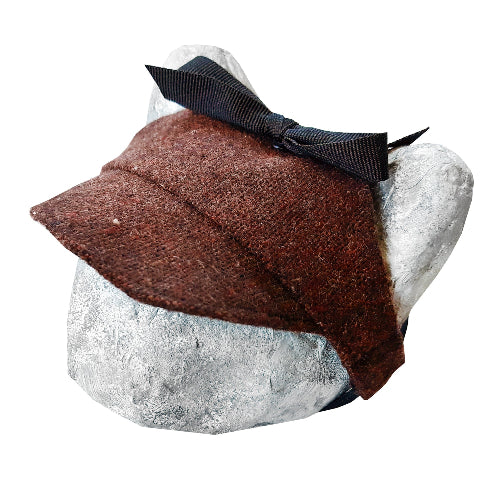 Tweed-style hat for a cat with a small brim and a black ribbon tied in a bow on top, shown on a grey textured surface.