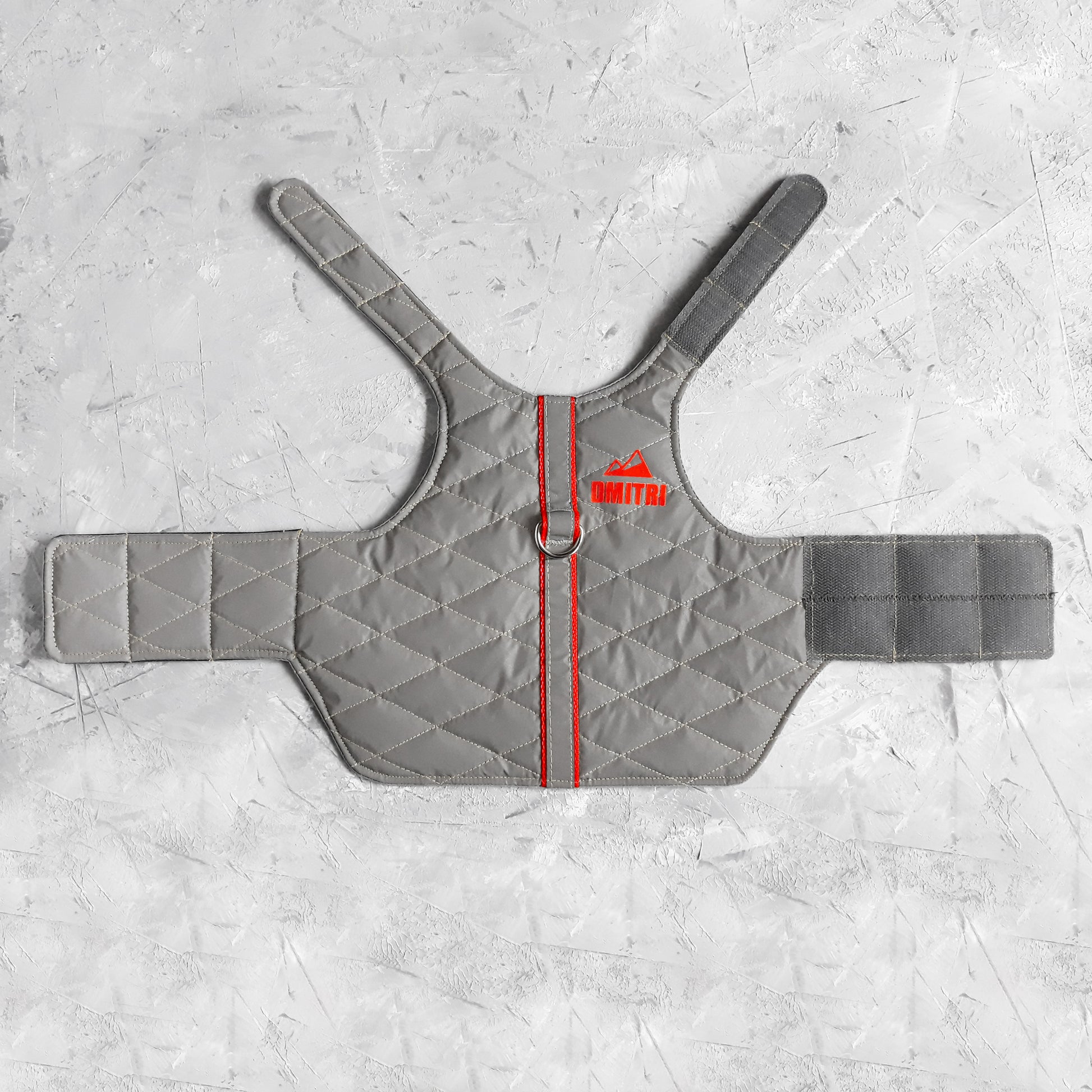 A quilted light grey cat harness with rred trim, a reflective stripe, personalized yellow "DMITRI" text with a mountain icon, and an Allcatsgood tag.
