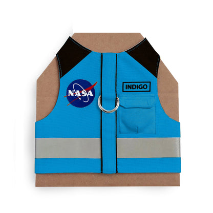 Blue cat harness with black shoulder accents, a NASA logo patch, a reflective silver stripe, and AirTag pocket