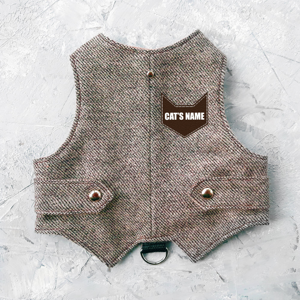 A light brown tweed cat harness with silver decorative buttons and a black D-ring