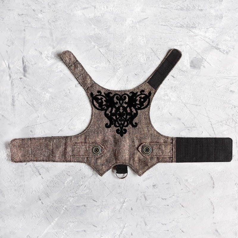 An overhead view of the inner lining of a brown tweed cat harness with a diagonal stripes pattern. The lining is a plain black fabric. A black leash attachment point with a silver D-ring is visible at the bottom.